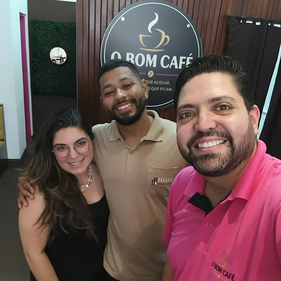 Três pessoas sorrindo juntas numa selfie dentro do O Bom Café